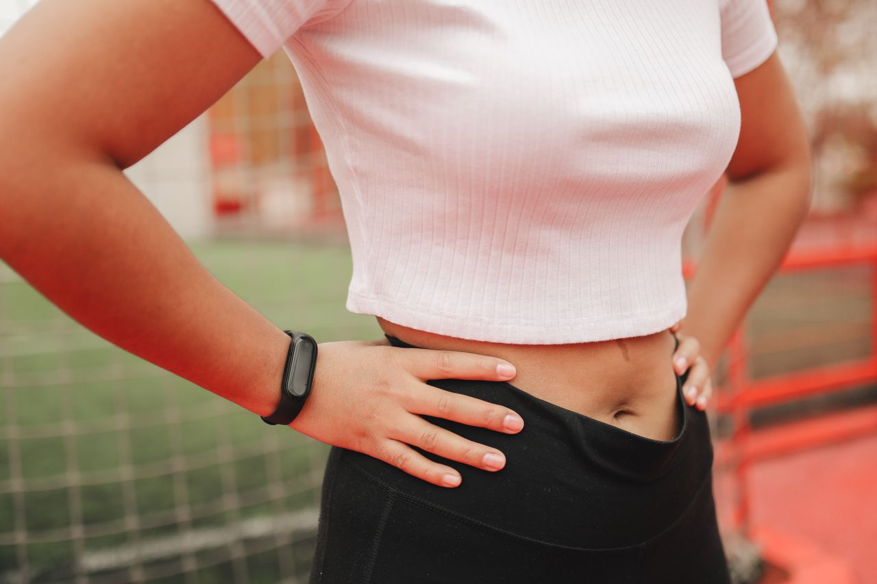 Close-up of a woman wearing a fitness tracker in a sporty setting, emphasizing active lifestyle.