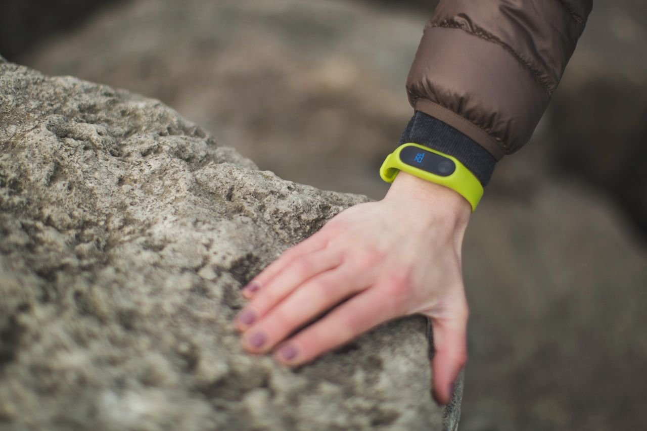 The Art of Drawing Readers In: Your attractive post title goes here Close-up of a hand with a fitness tracker touching a rock outdoors, showcasing exploration.